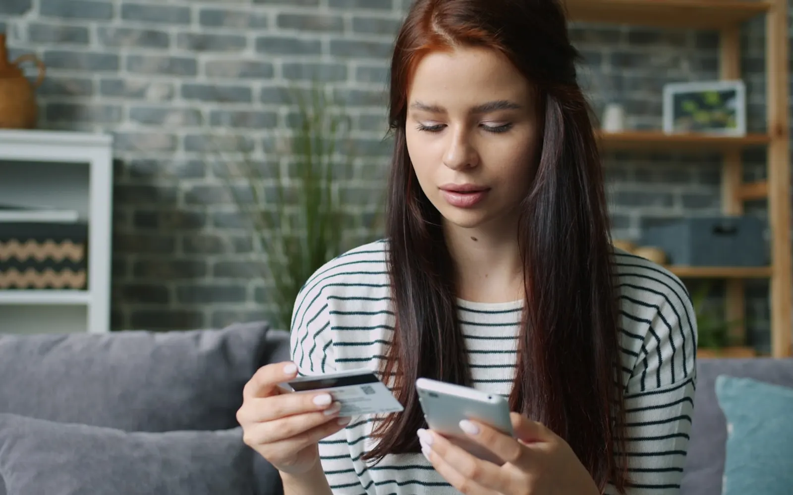 Woman holding a bank card alongside a smartphone
